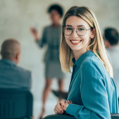 Happy young business woman attending business seminar, looking at camera and smiling